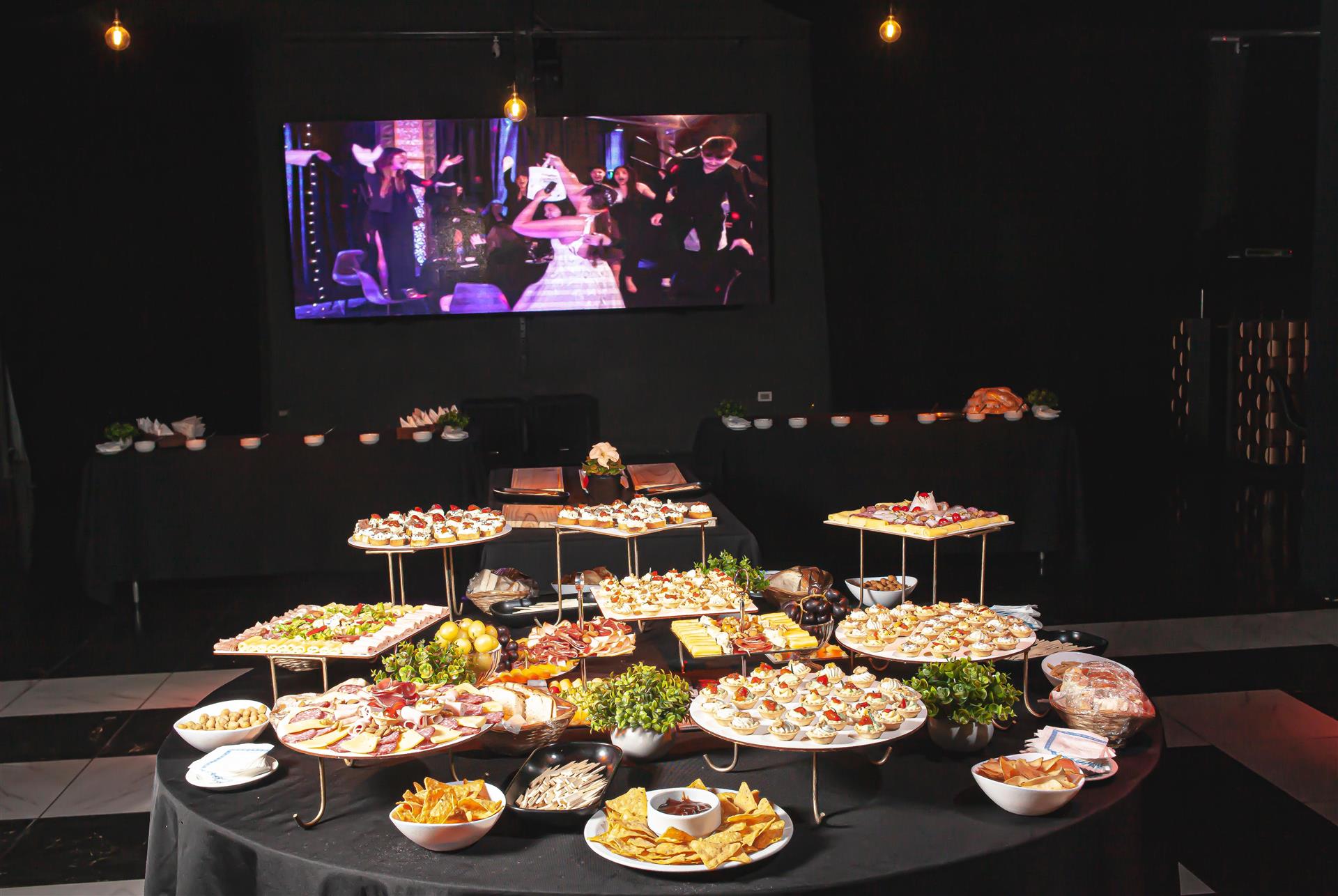 Mesa de recepción con bocados y pantalla al fondo