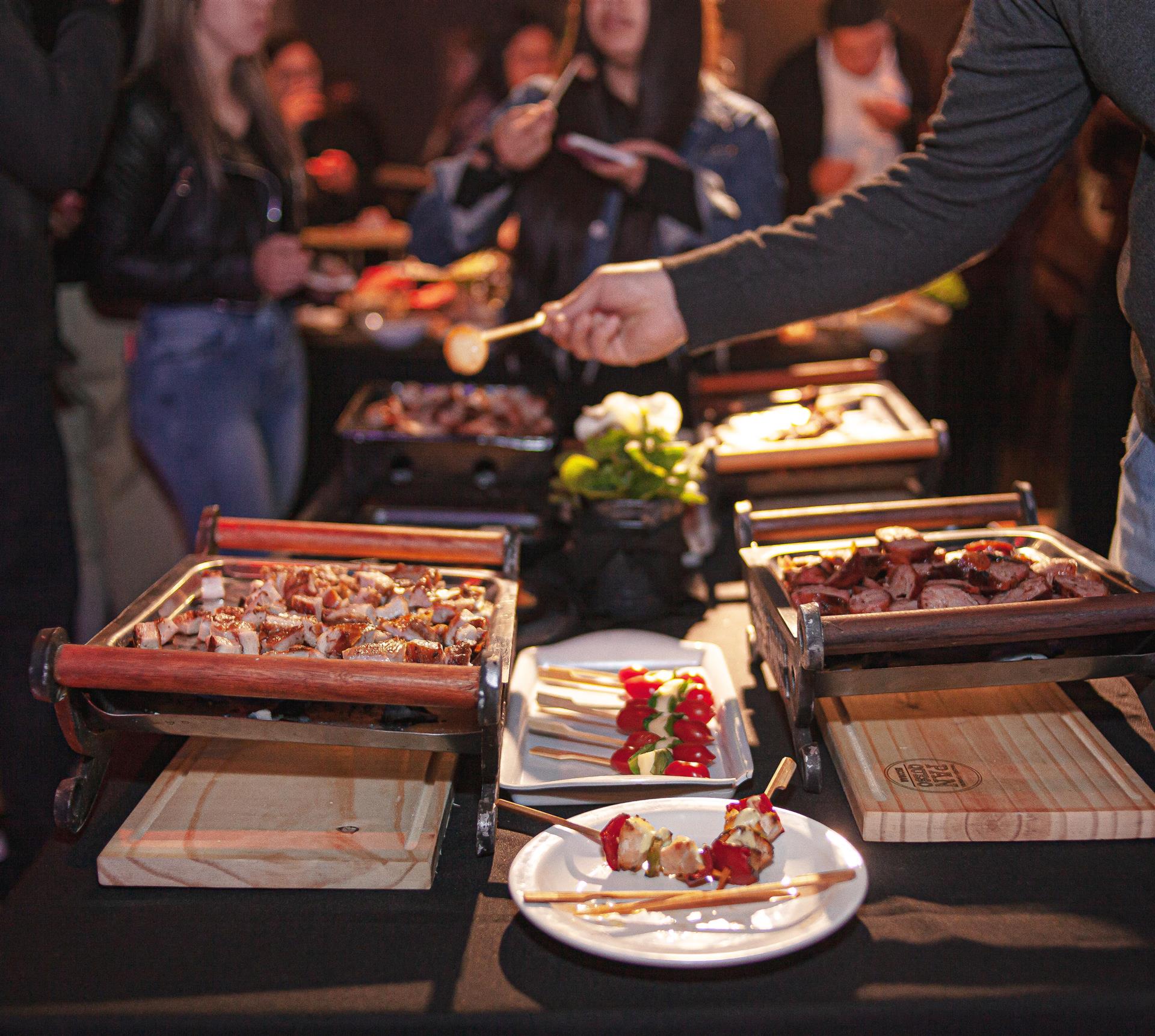Invitados sirviéndose en la mesa gastronómica